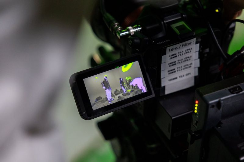 The LCD screen of a Canon EOS C80 showing a scene being filmed with a false colour overlay.