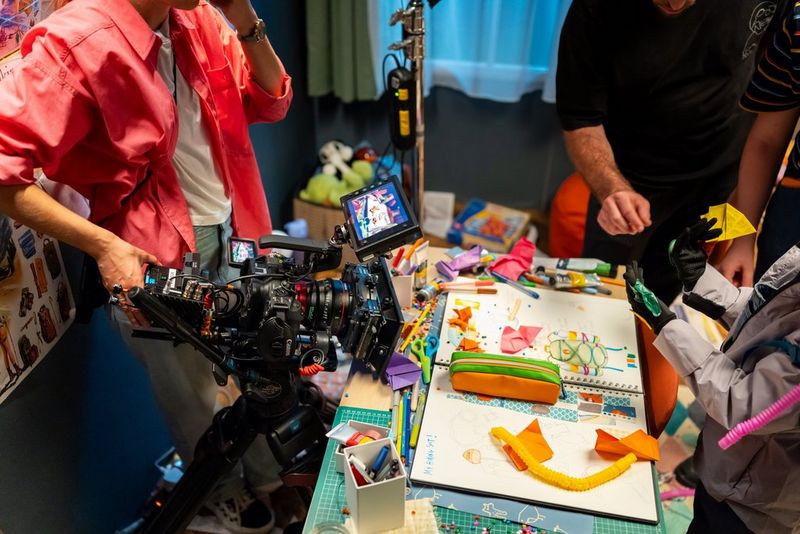 Carolina Nunes bedient een Canon EOS C80-camera die op een statief is bevestigd en legt een kleurrijke, creatieve scène vast.