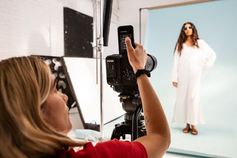 Cinematographer Carolina Nunes using the mode screen on a Canon EOS C80 to film a model standing in a studio with a light blue backdrop.