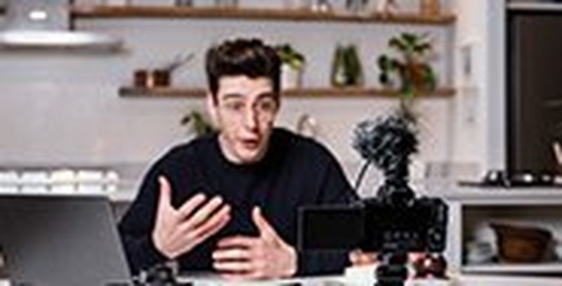 Vlogger Matt Adlard sat at a kitchen table filming a video on the EOS M50 Mark II.