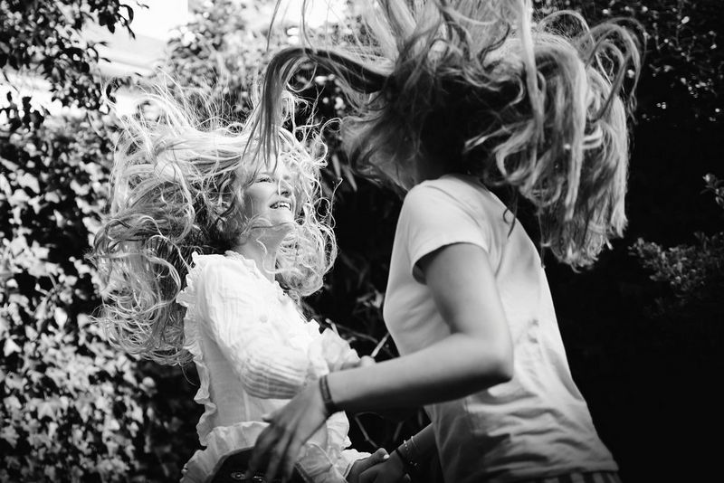 Een zwart-wit foto van twee tieners die rondspringen in een tuin.