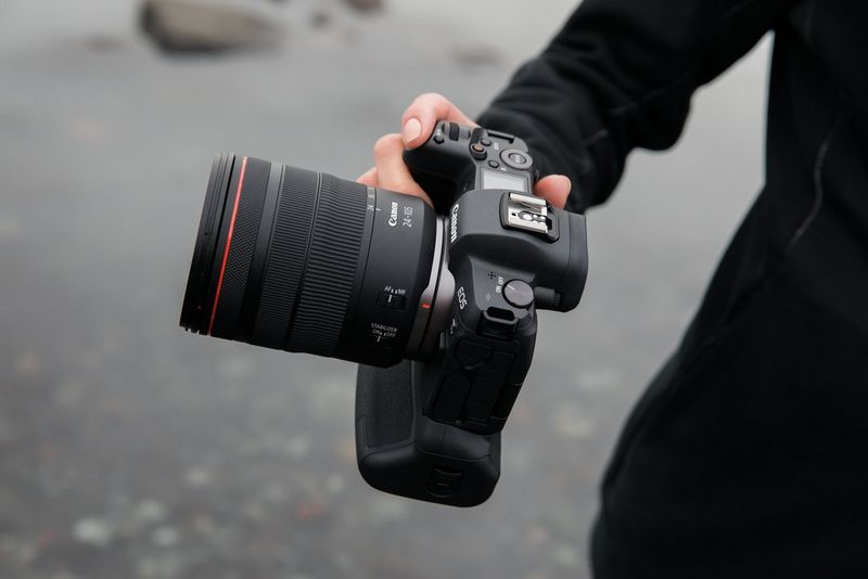 Een hand die een EOS R System-camera vasthoudt, met een Canon RF 24-105mm F4L IS USM-objectief.