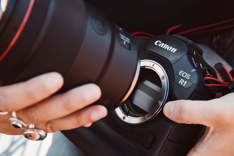 A lens being fixed to the RF mount of a Canon EOS R1 camera.