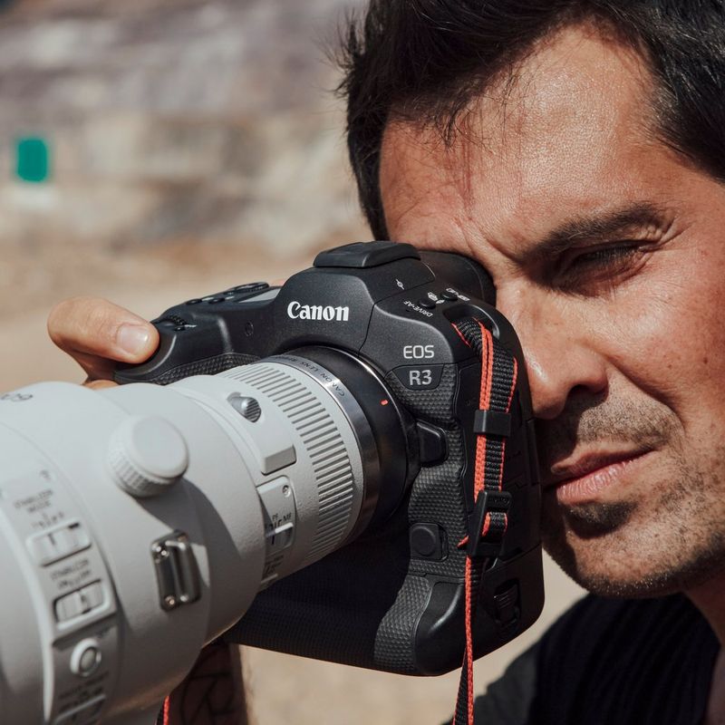 Photographer Vladimir Rys looks through the viewfinder of a Canon EOS R3 with a long lens attached.