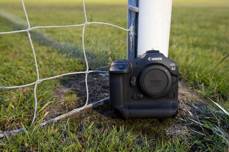 Een Canon EOS R3-camera die op de grond voor een doelpaal staat.