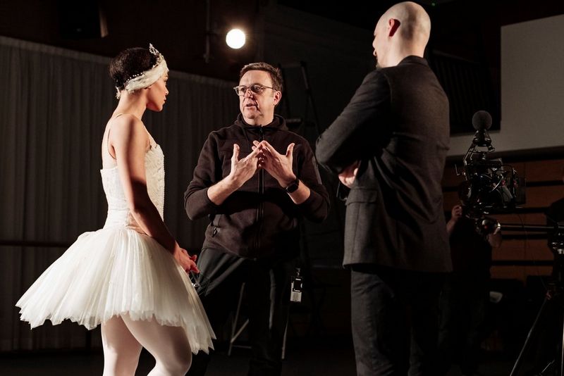 VR filmmaker Clive Booth stands between a ballerina in a white tutu and a man in a suit with his back to the camera.