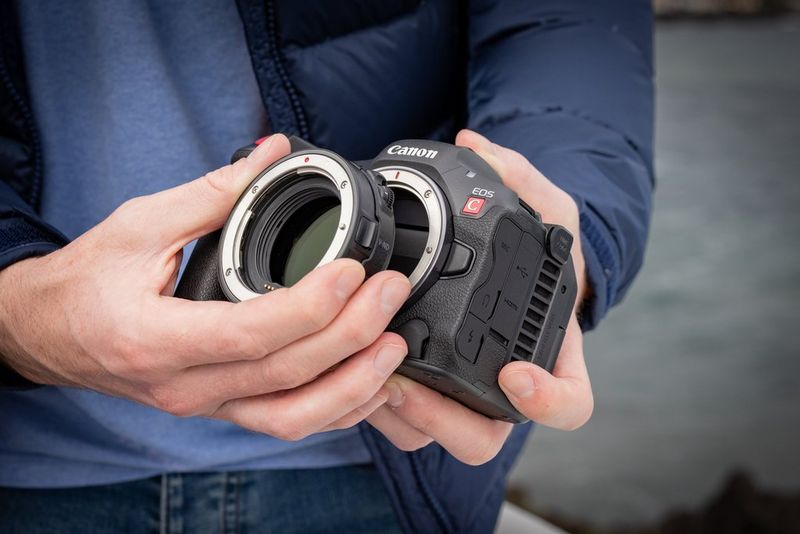 Hands attaching an EOS R adapter to a Canon EOS R5 C camera.