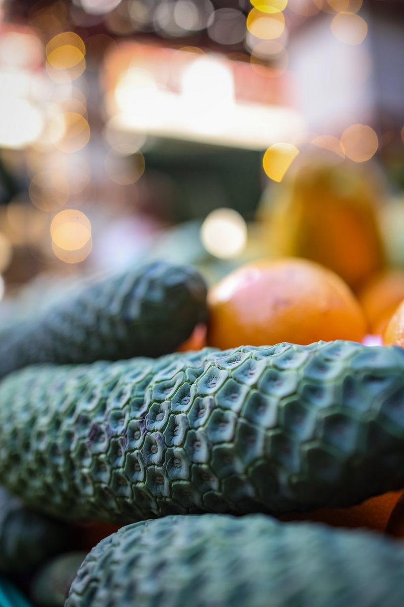 Primo piano di un incrocio tra banana e ananas (Monstera deliciosa), con altri frutti ed edifici sfocati sullo sfondo, realizzato con un obiettivo Canon RF 35mm F1.8 MACRO IS STM.