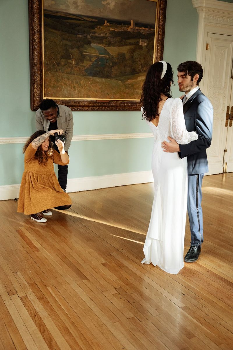 Alison Bounce crouches down to photograph a couple as they look into each other's eyes.