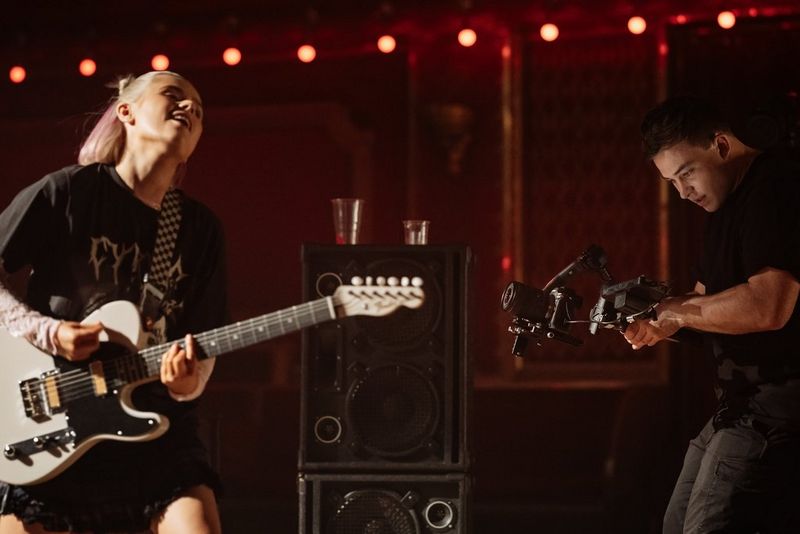Een filmmaker gebruikt een Canon EOS R5 Mark II-camera op een gimbal om opnamen te maken van een optredende gitarist.