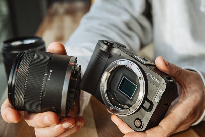 A zoom lens being attached to the Canon EOS R50 V, with the camera's APS-C sensor visible.