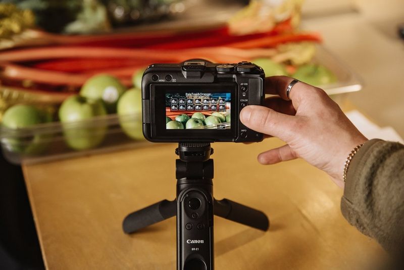 Un utente seleziona un filtro colore utilizzando il pulsante COLOR sul retro di una fotocamera Canon EOS R50 V montata su un'impugnatura per treppiede Canon HG-100TBR.