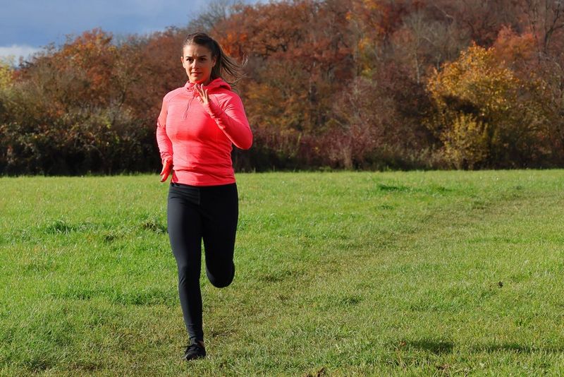 רץ הלובש בגד עליון בצבע אדום, שנתפס במחצית השמאלית של המסגרת קרוב למצלמה כשהוא רץ בשדה פתוח לעבר המצלמה ומאחוריו שורת עצים.