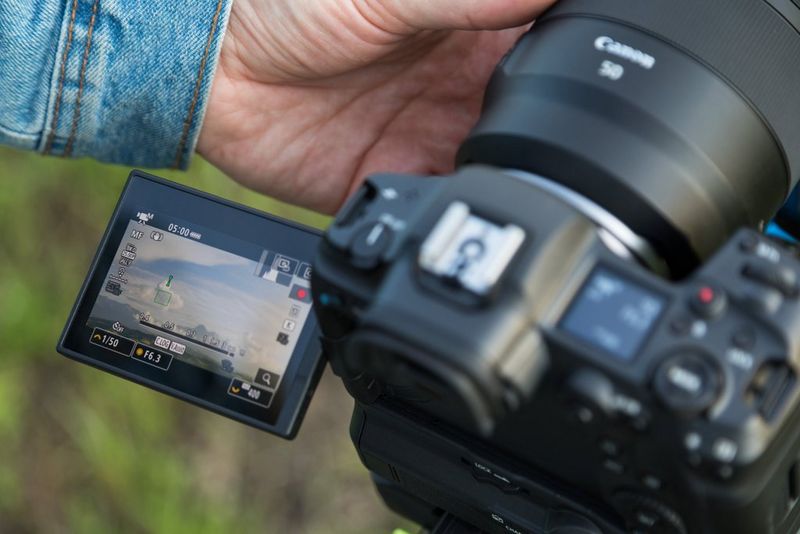 Een Canon-camera met het variangle touchscreen opzij geklapt en omhoog gekanteld, zodat de strandscène ervoor te zien is.