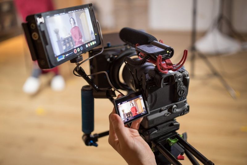 A Canon EOS R5 set up as a video camera, recording a seated woman in a red dress.