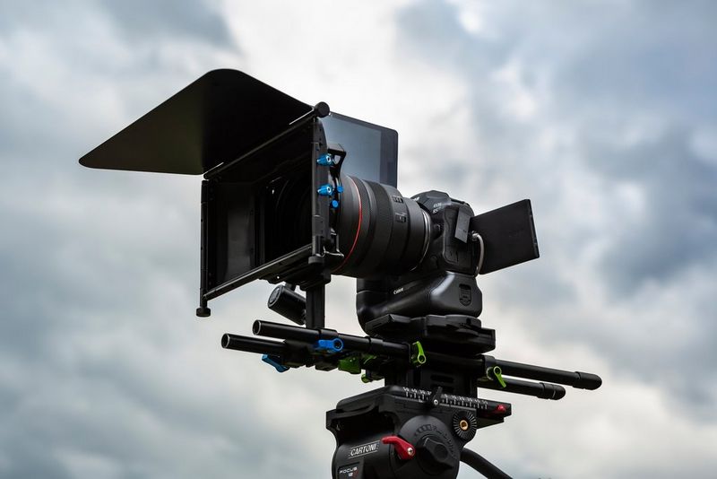 A Canon EOS R5 with a rectangular filter on front of the lens set up for filming on a tripod.