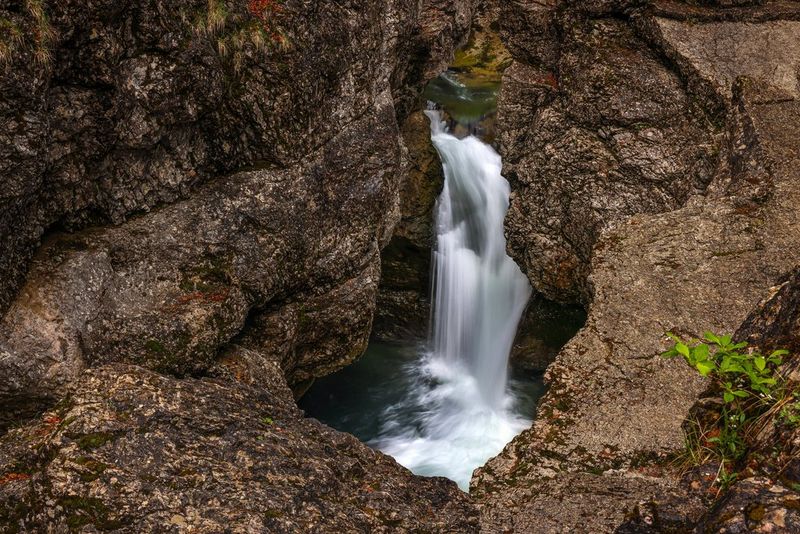 Een waterval stort in een poel tussen de rotsen, gefotografeerd met een lange sluitertijd om het vallende water te vervagen.