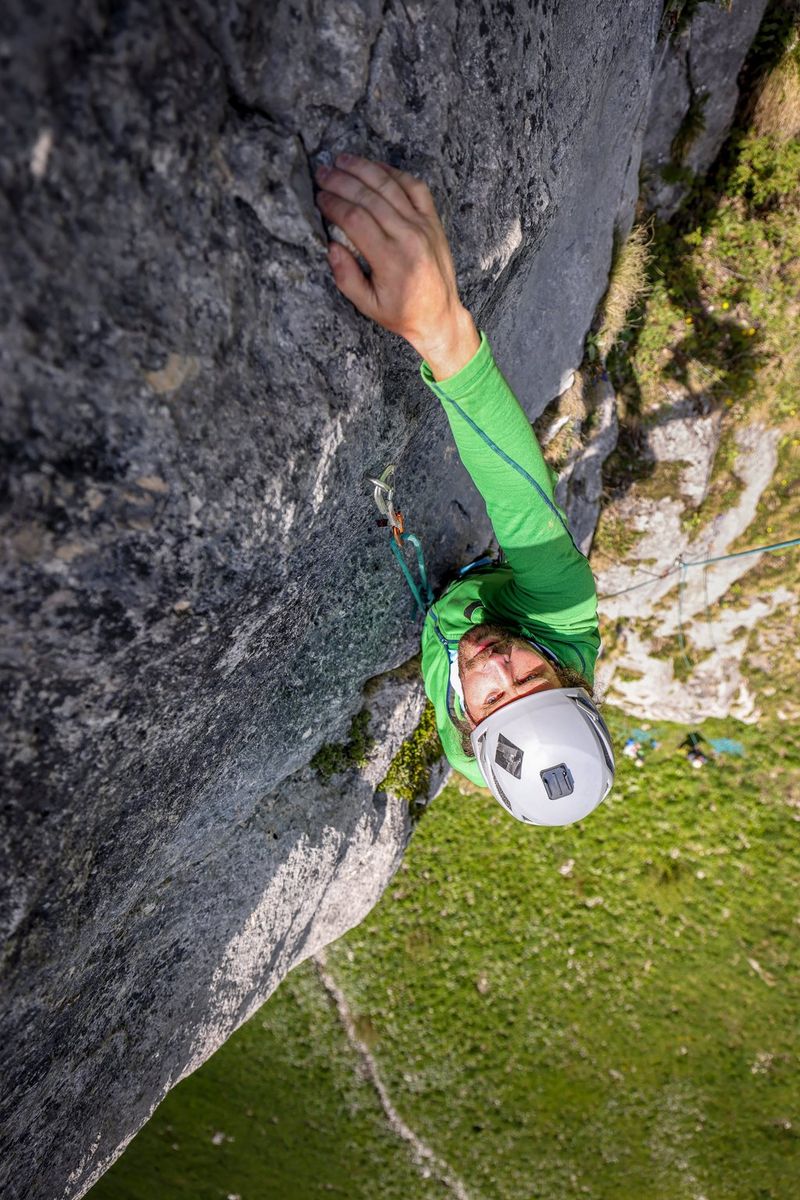 A top-down view of a rock climber scaling a sheer cliff face, photographed by adventure travel photographer Ulla Lohmann with a Canon EOS R5.