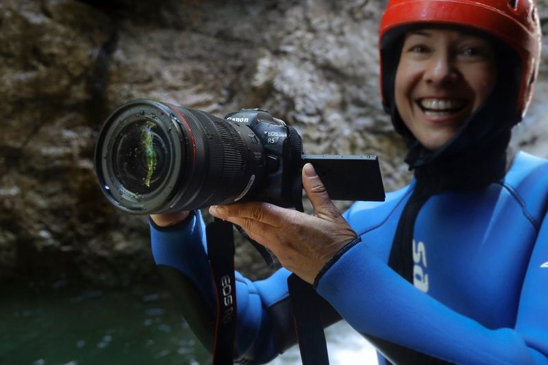 Ulla Lohmann in een blauwe wetsuit en met een rode helm met de Canon EOS R5 in het water.