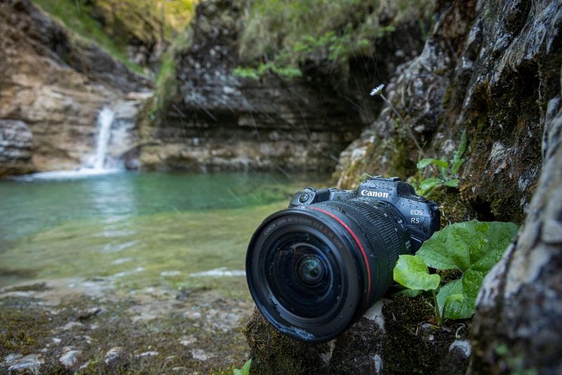 Een Canon EOS R5 met Canon RF 15-35mm F2.8L IS USM-lens op de oever van een poel met een waterval op de achtergrond.
