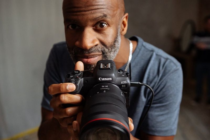 Le photographe de mode Kid Circus regarde l'appareil photo en tenant un Canon EOS R5.