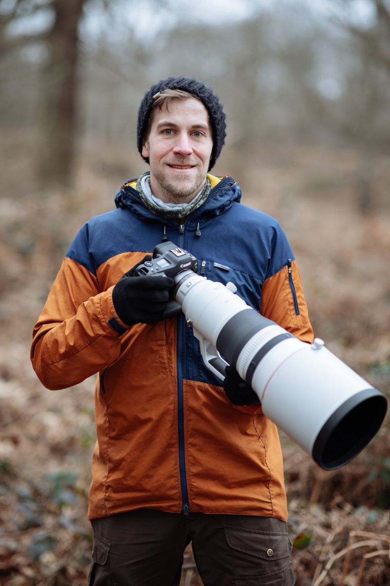 Il fotografo naturalista e naturalista Radomir Jakubowski in una foresta con una fotocamera mirrorless Canon e un teleobiettivo Canon RF.