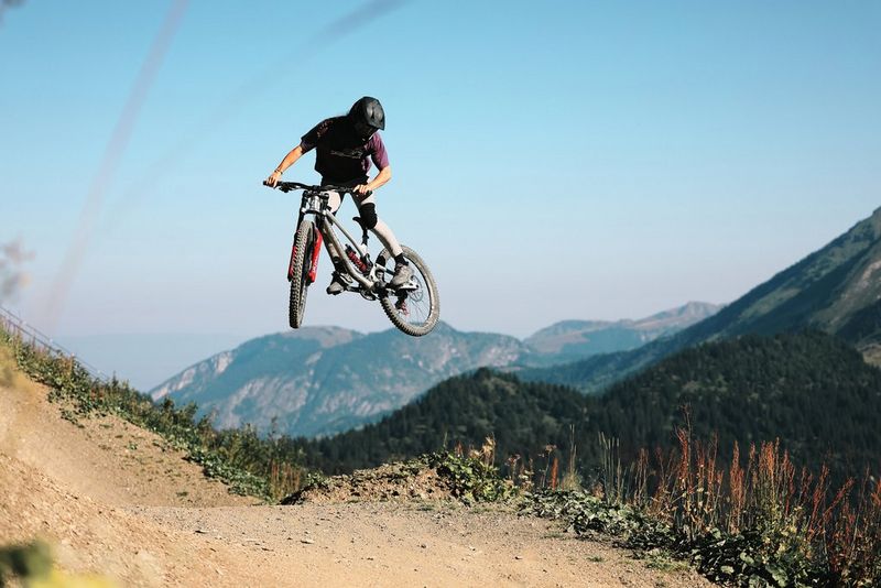 Een fietser doet een stunt in de lucht. Op de achtergrond zijn bergen te zien. Gefotografeerd met een Canon EOS R6 Mark II.