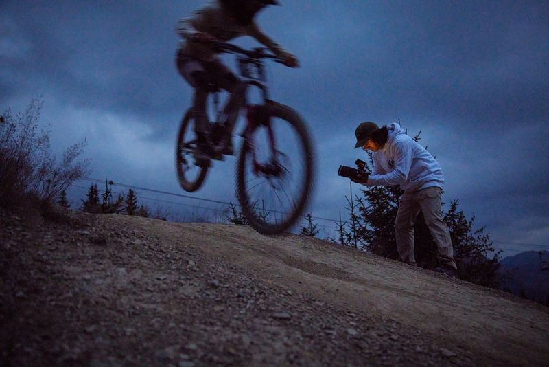 Un photographe pointe le Canon EOS R6 Mark II vers un vététiste alors qu'il saute au sommet d'une colline.