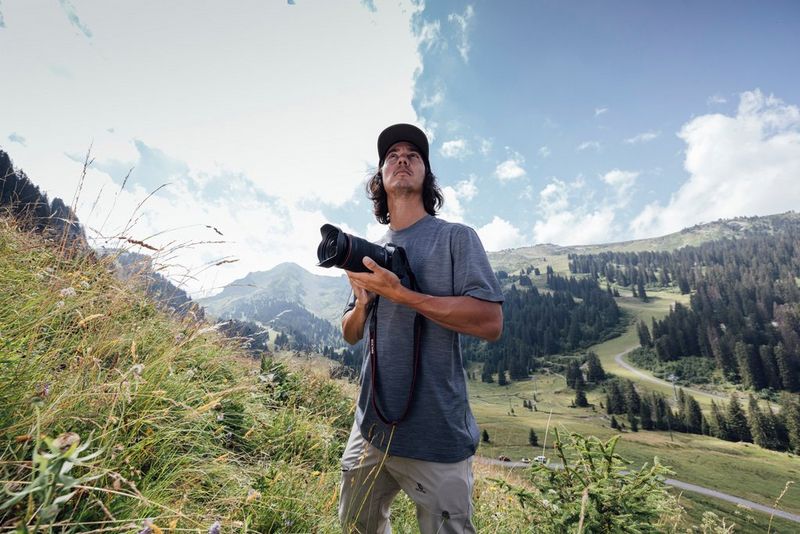 Teddy Morellec staat op een berghelling en kijkt naar de lucht met een Canon EOS R6 Mark II-camera in de hand.