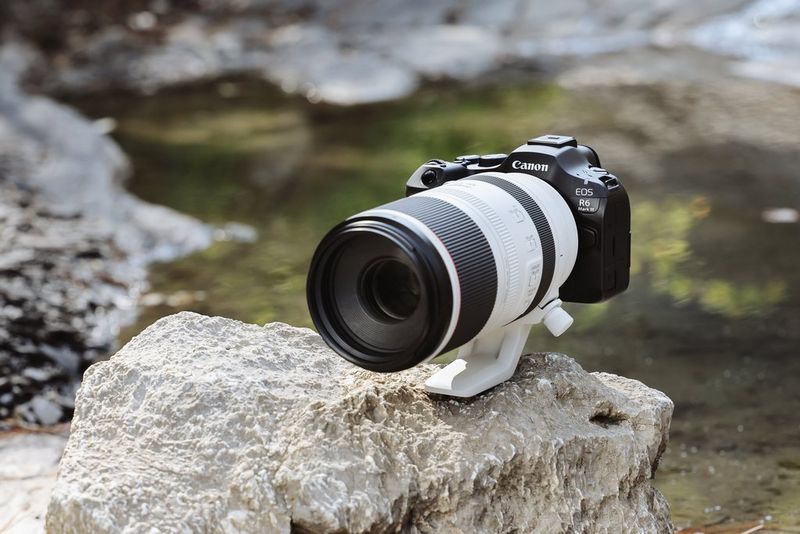 Canon EOS R6 Mark III con un teleobiettivo zoom RF è posizionata su una roccia vicino a un fiume.