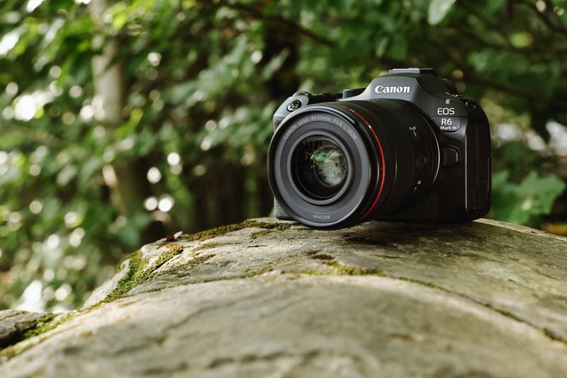 Una fotocamera EOS R6 Mark III con obiettivo RF serie L fotografata all'aperto, con uno sfondo morbido e naturale.