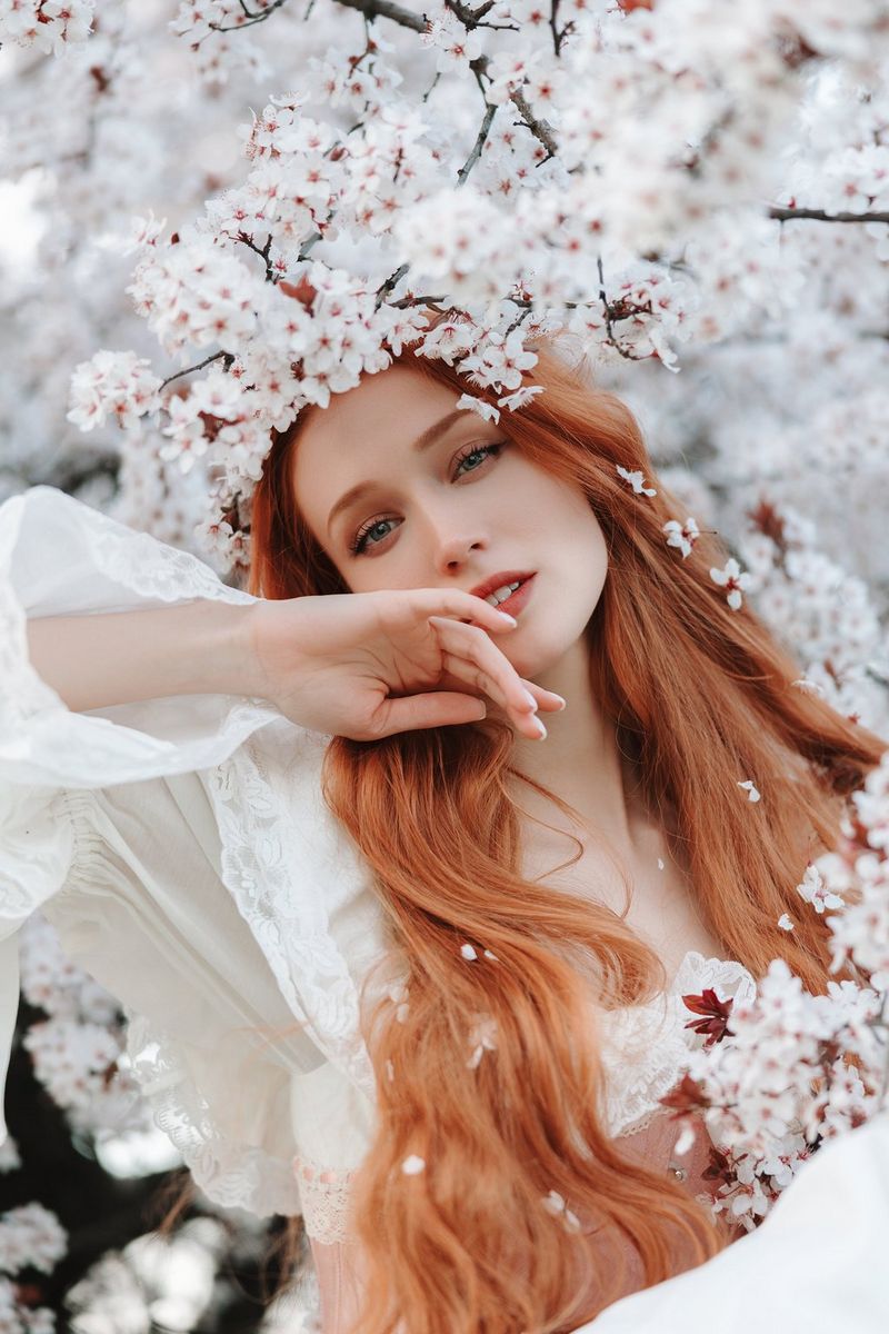 A portrait of a young woman with long red hair against a blurred background, taken on a full-frame Canon EOS camera.  