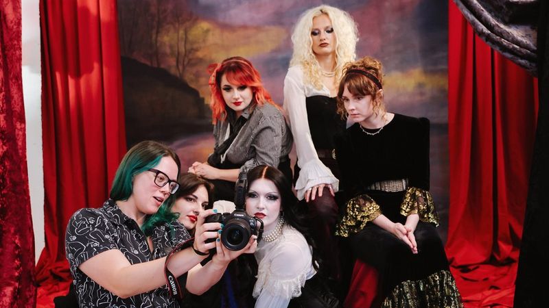 Photographer Corinne Cumming showing an image on the back of the Canon EOS R6 Mark III to the members of a band she is photographing in a studio. 