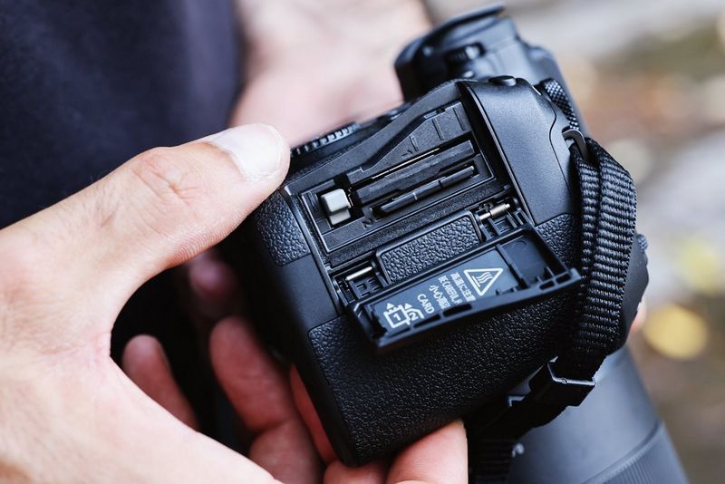Canon EOS R6 Mark III viene mostrata con il vano per due schede di memoria aperto, rivelando una scheda CFexpress e una SD.