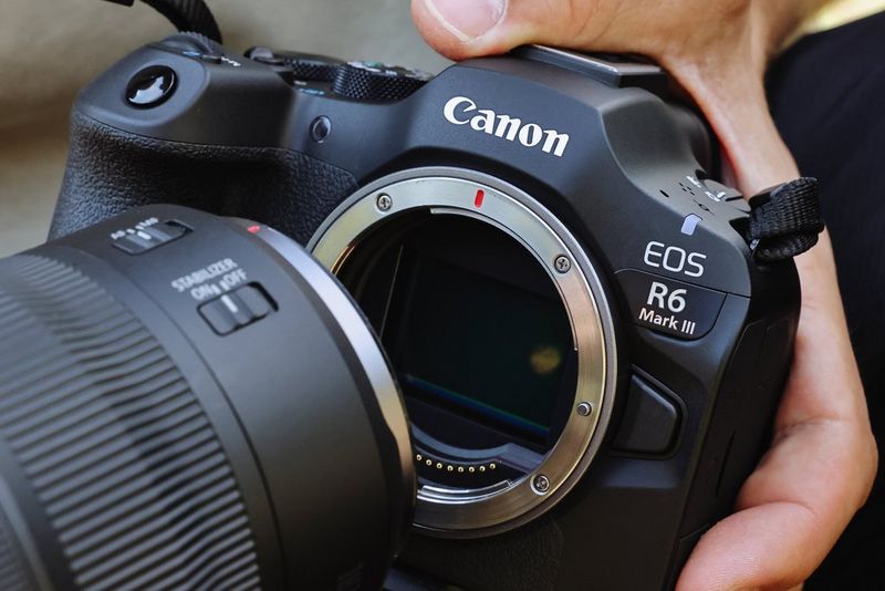 Un obiettivo RF viene montato su Canon EOS R6 Mark III, con il sensore CMOS full frame da 32.5 MP e i contatti dell'innesto RF ben visibili.