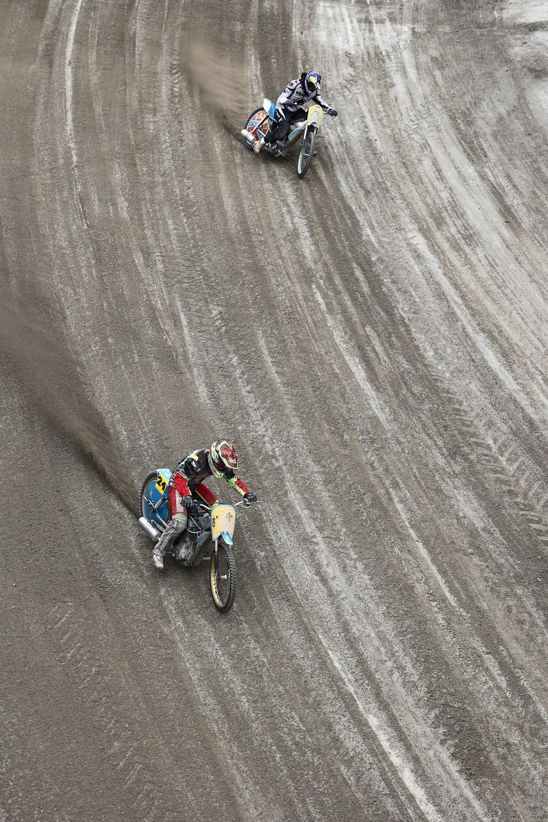 A view from a high angle of a dirt bike track with two riders racing each other.
