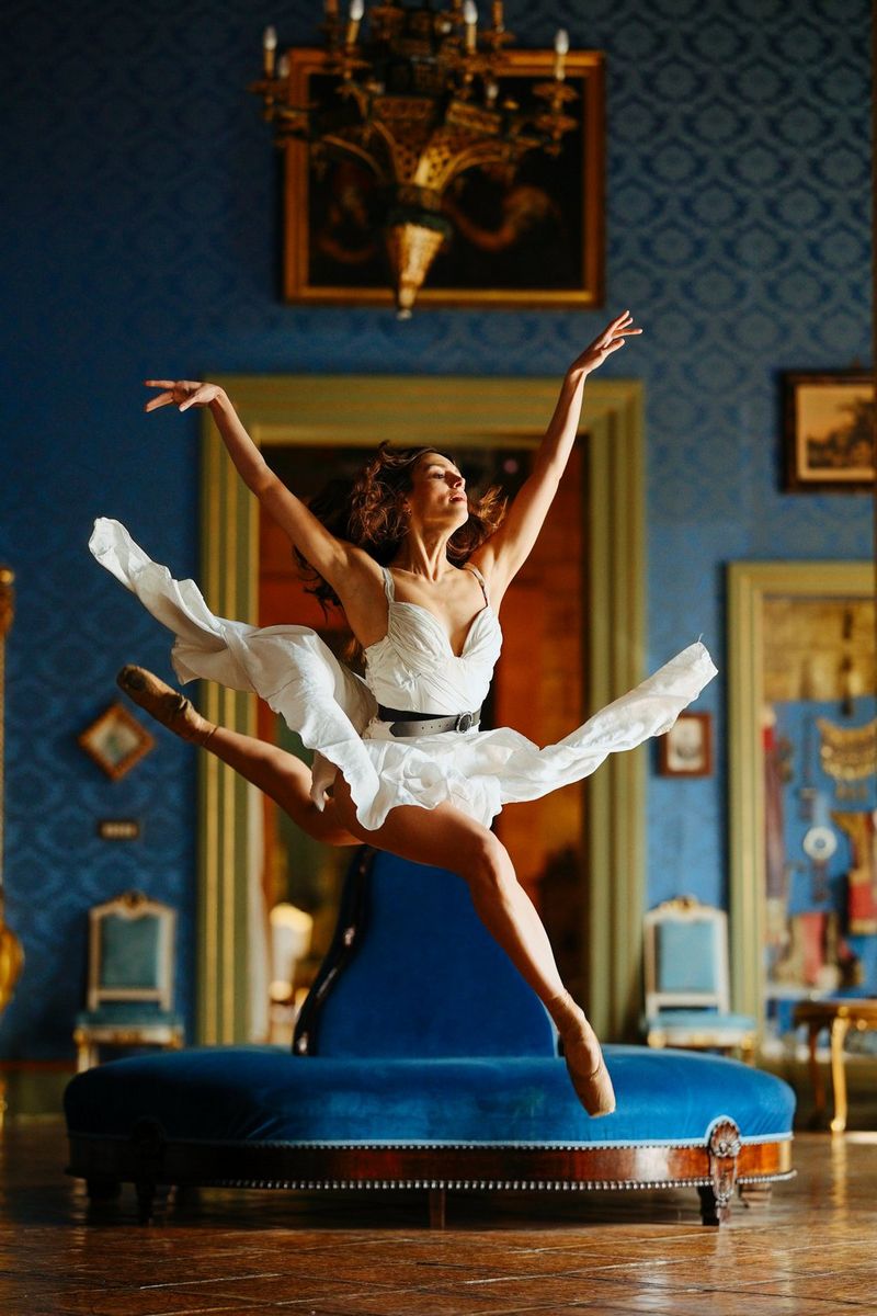 A ballerina leaps across an ornately decorated room.