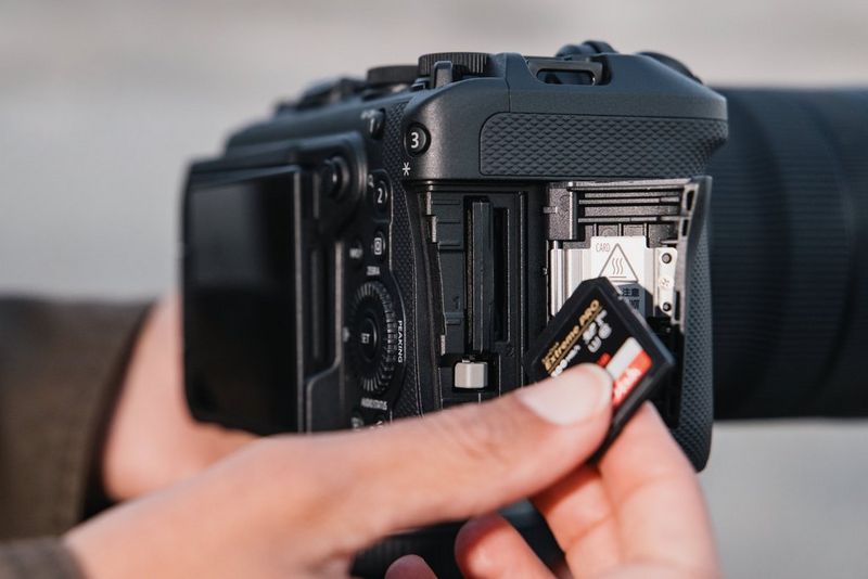 Die Speicherkartensteckplätze der Canon EOS R6 V, mit einer CFexpress-Karte in einem Kartensteckplatz. Eine SD-Karte wird in den anderen Steckplatz eingelegt.