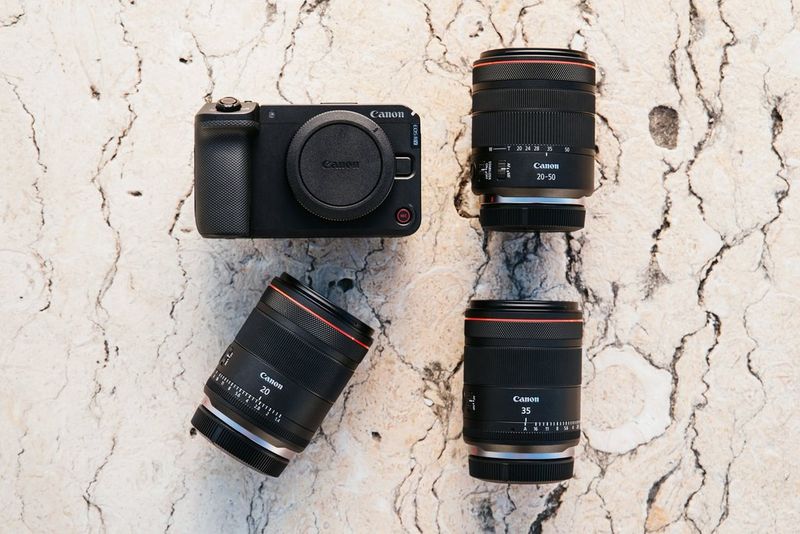Fotoaparat Canon EOS R6 V, skupaj z objektivom Canon RF 20-50mm F4L IS USM PZ, objektivom Canon RF 20mm F1.4L VCM in objektivom RF 35mm F1.4L VCM na razpokanih betonskih tleh.