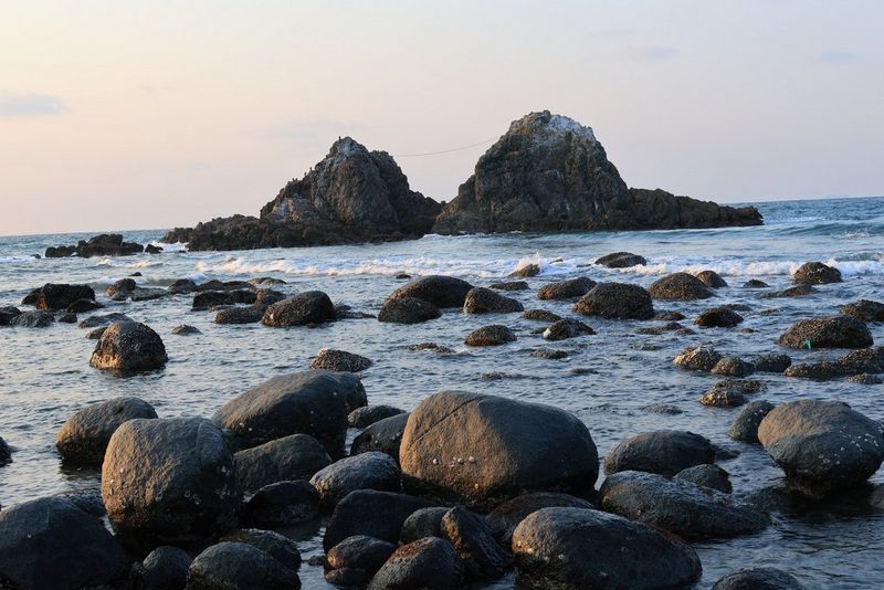 En udsigt over klipper i lavt vand med retning mod et klippefremspring i havet, som er fotograferet med kameraets Auto Level-funktion slået fra, hvilket resulterer i et vippet look.