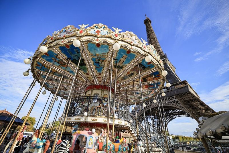 An ultra-wide view of a carousel beneath the Eiffel Tower, taken on a full-frame Canon camera.