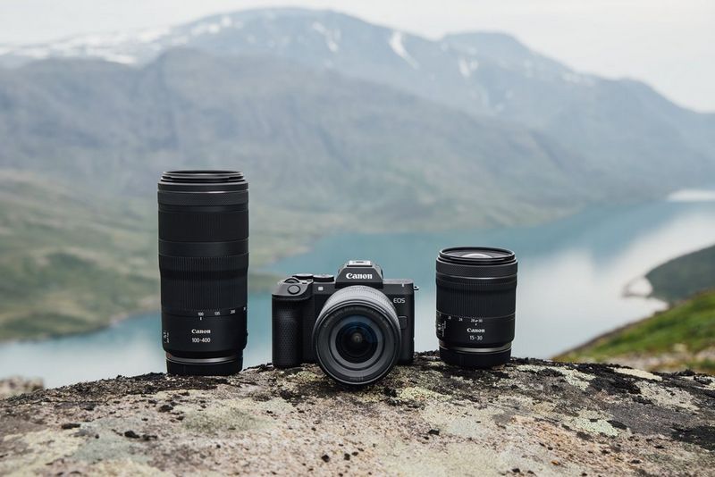 Egy Canon EOS R8 Mark II és két RF objektív egy európai hegyvidéki táj előtt.