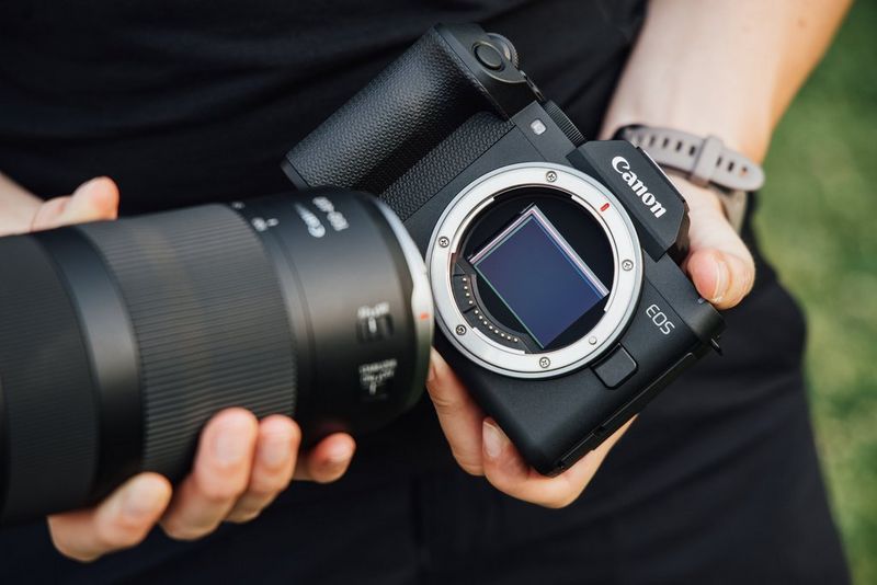 A Canon RF 100-400mm F5.6-8 IS USM being attached to a Canon EOS R8 Mark II, with the camera's full-frame sensor visible.