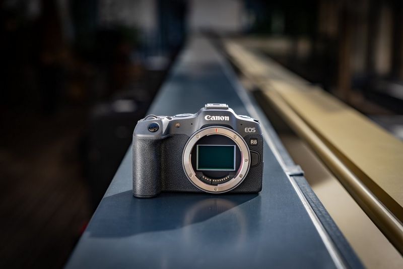 A Canon EOS R8 sits on a blue ledge. The foreground is in sharp focus while the background is blurred.
