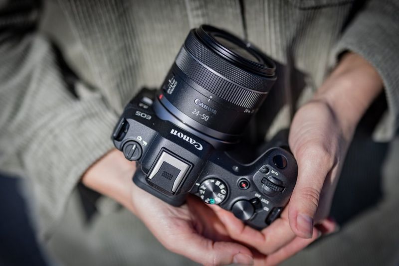 A close-up of hands holding a Canon EOS R8 camera.