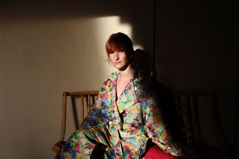 A portrait taken on a Canon EOS R8 showing a model in a colourful outfit illuminated by a patch of light and surrounded by shadows.
