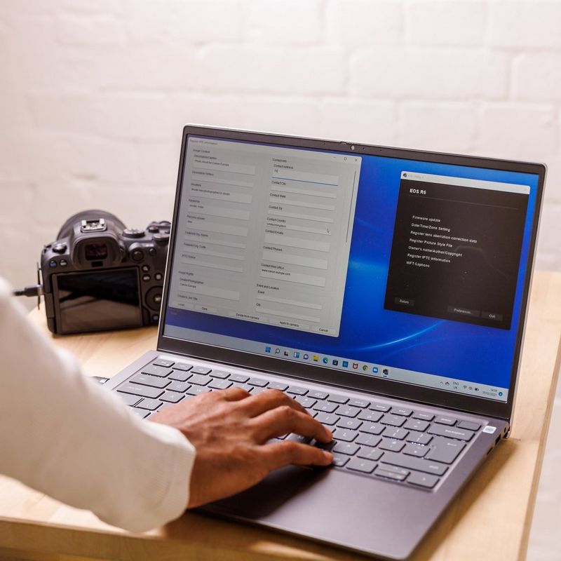 Рука на клавиатуре ноутбука. На экране ноутбука открыто ПО Canon EOS Utility.