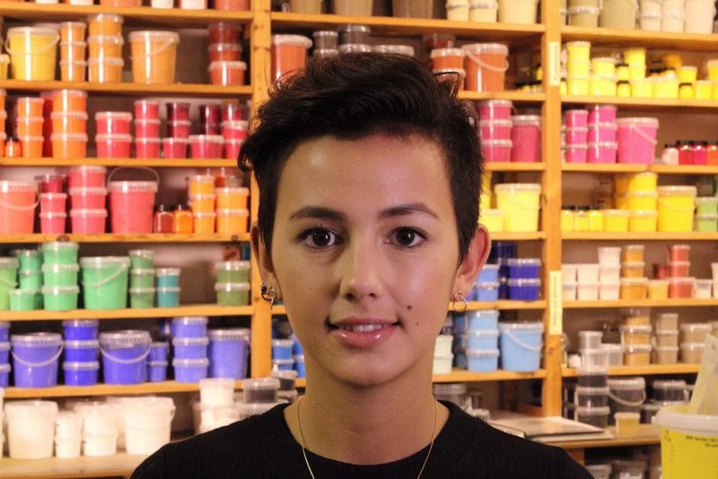 A portrait of a young woman against a background of shelves full of colourful items, all almost as sharp as the woman.