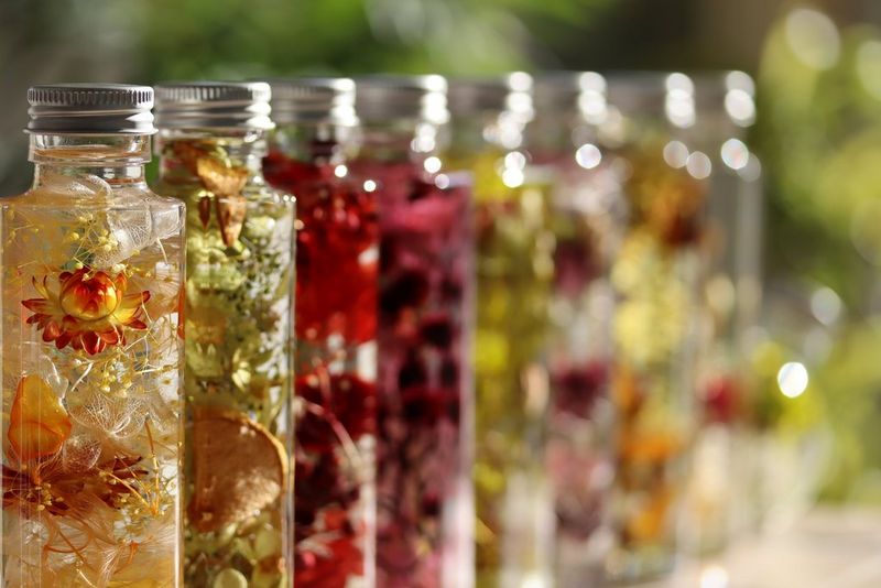 A row of small glass bottles filled with colourful flowers and decorative liquids, photographed with a shallow depth of field.