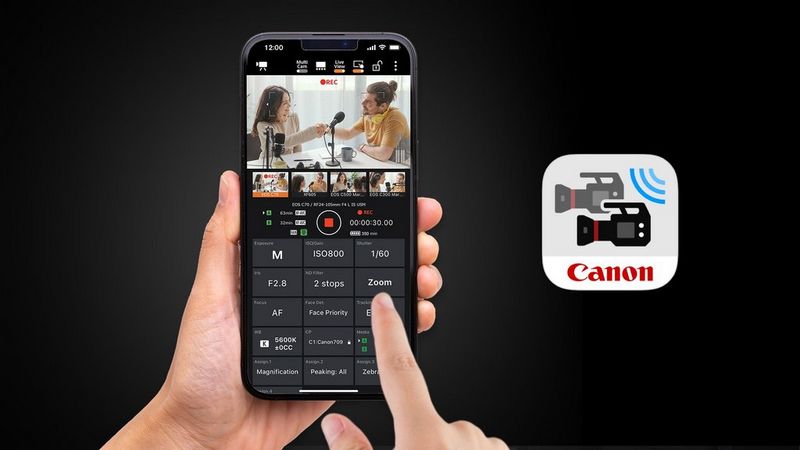 A pair of hands holding a smartphone showing the Canon Multi-Camera Control smartphone app.